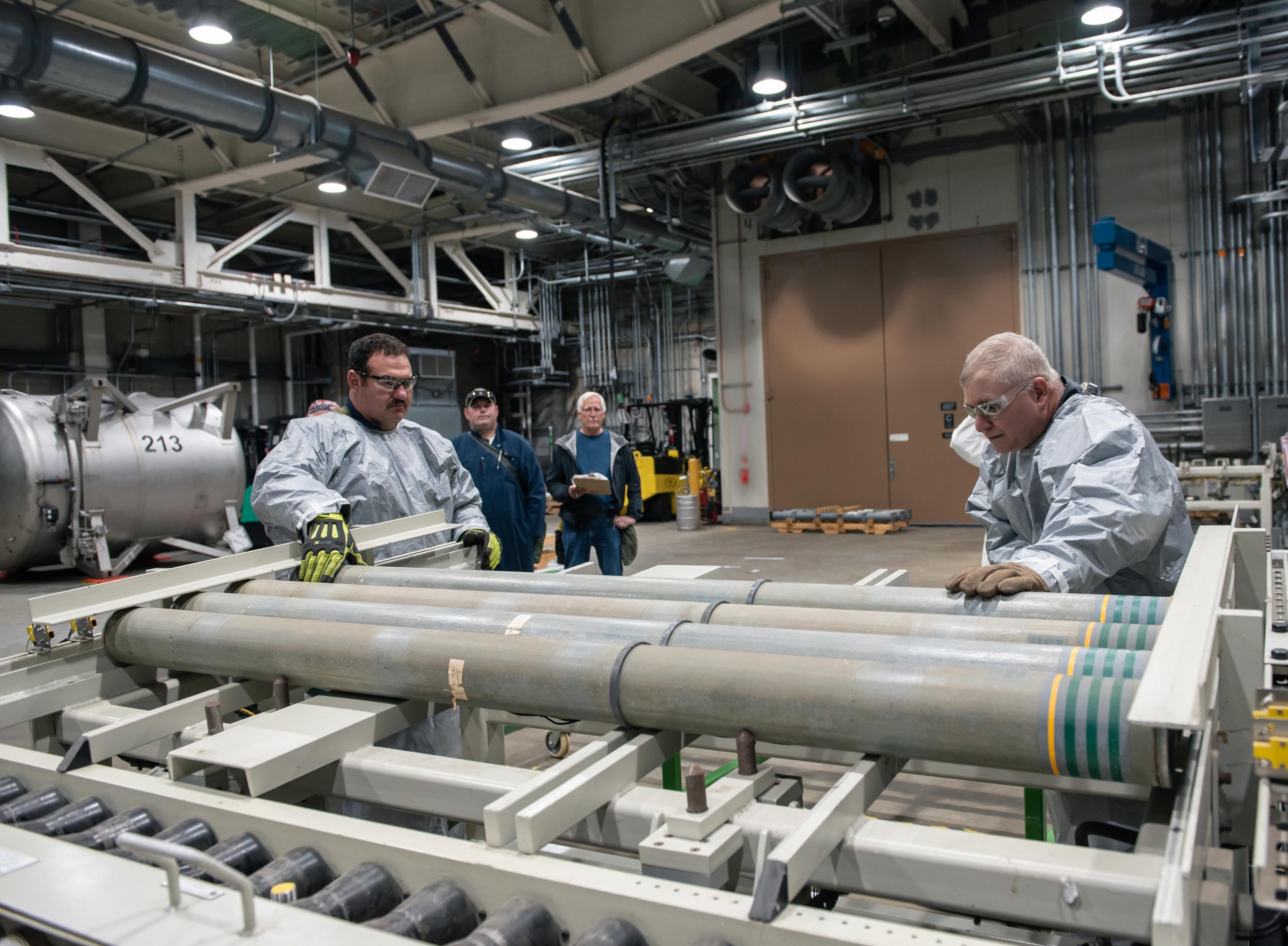 Blue Grass Chemical Agent-Destruction Pilot Plant operators place the first M55 rockets containing VX nerve agent on a conveyor to begin the destruction process July 9. This marks the fourth of five destruction campaigns to begin at the Blue Grass Army Depot. (A portion of this photo has been blurred in accordance with Department of Defense guidelines.)
